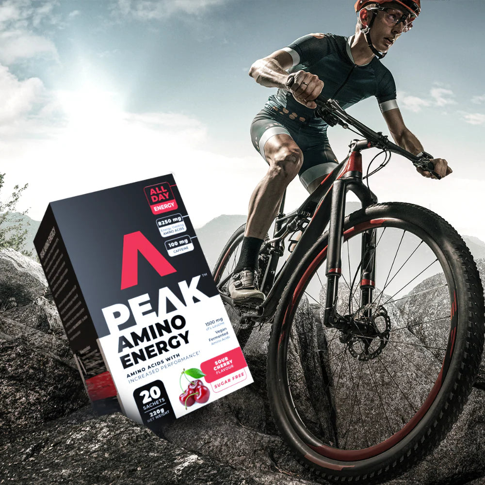 Person riding a bicycle with a Peak Amino Energy supplement box in the foreground Muscle Mecca