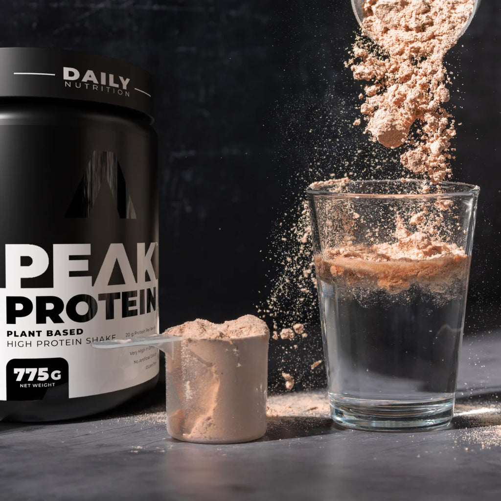 Peak Protein plant-based high protein shake being poured into a glass with a container in the background. Muscle Mecca