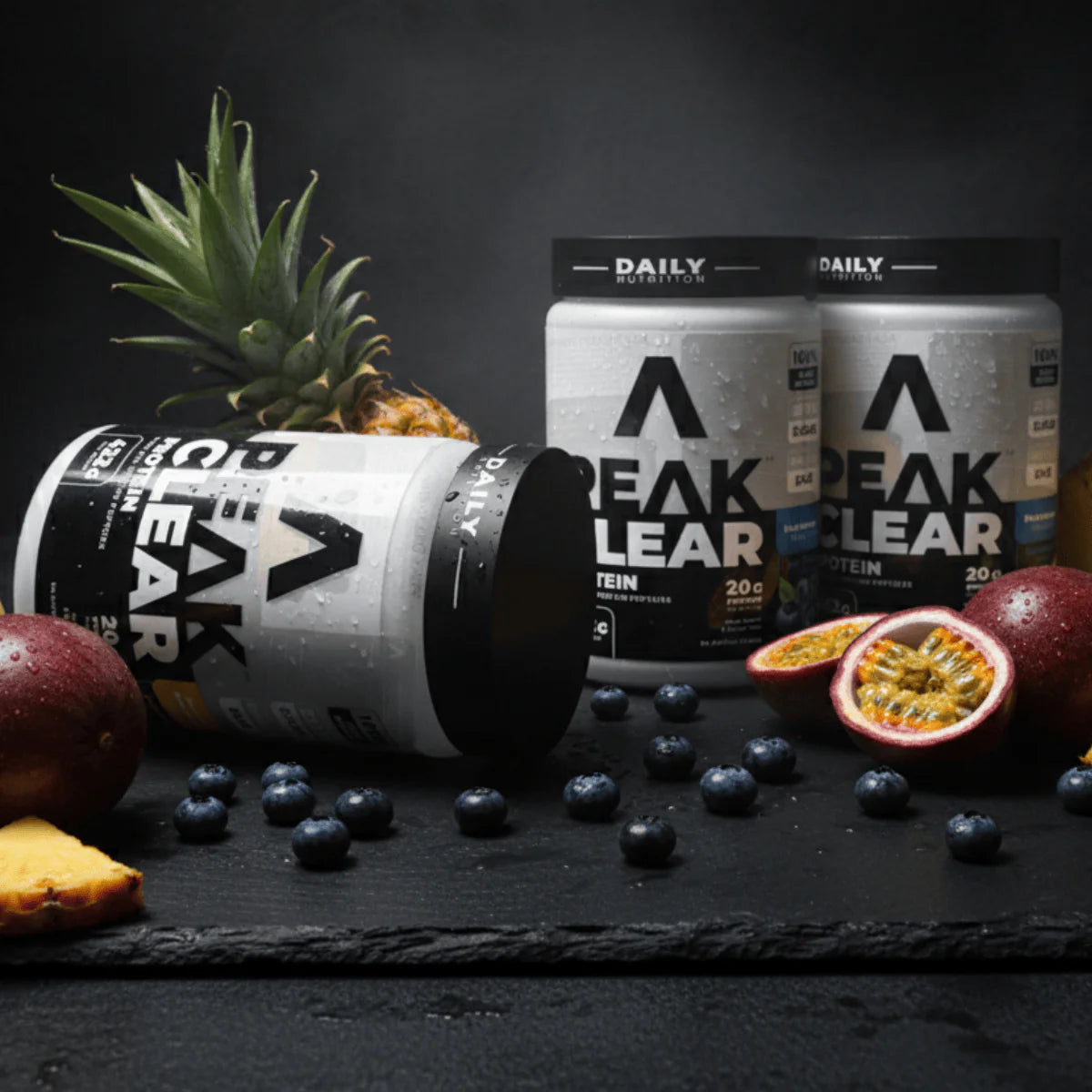 Peak Clear protein containers with fruits on a dark surface Muscle Mecca