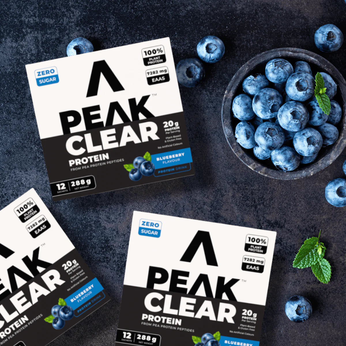 Peak Clear protein packaging with blueberries on a dark surface Muscle Mecca